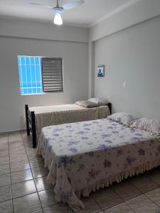 a bedroom with two beds and a window at Apartamento completo com 2 suítes in Praia Grande