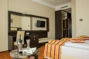 Cette chambre comprend un lit, une table et un miroir. dans l'établissement Salis Hotel & Medical Spa, à Turda