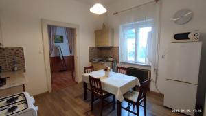 a kitchen with a table and chairs and a kitchen with a refrigerator at ENZO Apartman Gyula in Gyula