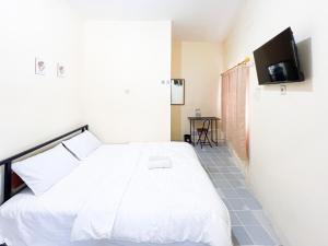 Un dormitorio con una cama blanca y un televisor de pantalla plana. en Graha Indah Ngagel Surabaya RedPartner, en Surabaya