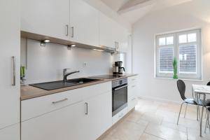 a white kitchen with a sink and a stove at Strandallee 53 Sonnendeck in Haffkrug