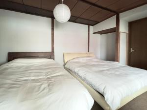 a bedroom with two beds and a pendant light at Private house Oheso 40minutes from Sapporo,4 free parking, long stay,16people in Tōbetsu