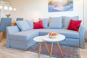 a blue couch with red pillows and a bowl of fruit on a table at Panoramic Panoramablick Ostsee in Hansaland