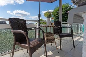 two chairs and a table on a balcony with an umbrella at Seepferdchen Blomen in Hansaland +31 photos
