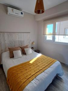 a bedroom with a large bed with a yellow blanket at Chill Depto en Zona Centro in Chascomús