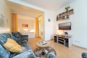 Una sala de estar con un sofá y un televisor. en Strandappartements am Leuchtturmweg Leuchtturmblick, en Kellenhusen