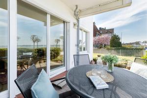 a patio with a table and chairs and a view of the ocean at Villa Fördestrand Sehpferdchen in Laboe