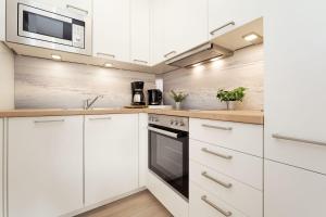 a white kitchen with white cabinets and a microwave at Haus Wiking- Nordstern in Grömitz