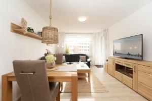 a living room with a table and a television at Haus Wiking- Nordstern in Grömitz