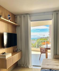 a bedroom with a television and a large window at Apartamento NOvo na Praia do Morro Temporada Wi-Fi, Vista Mar, garagem, varanda grande in Guarapari