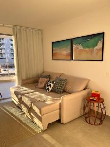 a couch in a living room with two pictures on the wall at Apartamento NOvo na Praia do Morro Temporada Wi-Fi, Vista Mar, garagem, varanda grande in Guarapari +8 photos