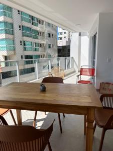 a wooden table and chairs in a room with a balcony at Apartamento NOvo na Praia do Morro Temporada Wi-Fi, Vista Mar, garagem, varanda grande in Guarapari