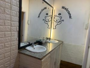 a bathroom with two sinks and a mirror with a hello kitty sign at Chút Homestay in Xuan An