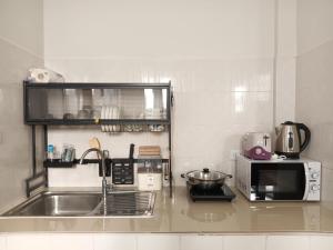 a kitchen with a sink and a microwave at Sila Apartment in Ban Thalat Choeng Thale