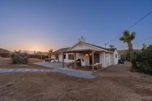 una pequeña casa blanca con una puesta de sol en el fondo en License To Chill, en Yucca Valley