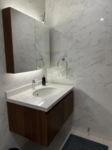 a white bathroom with a sink and a mirror at Sea & Lagoon View in The Wave in Muscat
