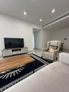 a bedroom with a tv and a chair and a bed at Sea & Lagoon View in The Wave in Muscat