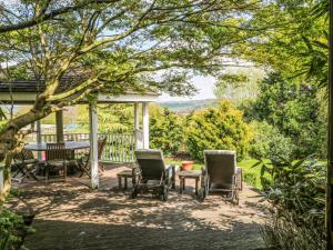 a patio with chairs and a table on a deck at Frog Meadow Barn in Biddulph