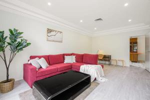 a red couch in a living room with a table at Liverpool Oasis 5BR Home for Groups and Families in Liverpool