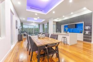 Un comedor y una cocina con mesa y sillas de madera. en Luxury 5BD house w water view in Melrose Park, en Sídney