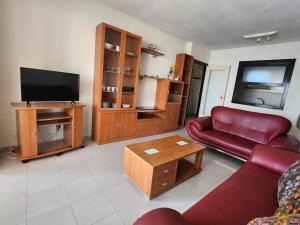 a living room with a red couch and a flat screen tv at Amaika, cerca de playa, con aparcamiento y piscina in Calpe