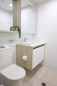 un bagno bianco con un water e un lavandino di Sun-Kissed Coastal Comfort Pool,Gym,Beach,BBQ a Gold Coast