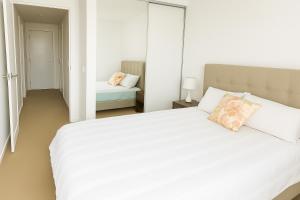 una camera da letto con un letto bianco e un cuscino sopra di Sun-Kissed Coastal Comfort Pool,Gym,Beach,BBQ a Gold Coast Altre 7 foto