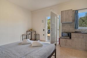 a white bedroom with a bed and a kitchen at Panagis Apartments in Argostoli