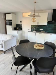 a kitchen and dining room with a black table and chairs at Ruimte, privacy en comfort op de Veluwe, inclusief 2 fietsen & linnengoed in Nunspeet