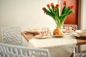 einen Tisch mit einem Teller Croissants und einer Vase Blumen in der Unterkunft Apartment Sapa in Split