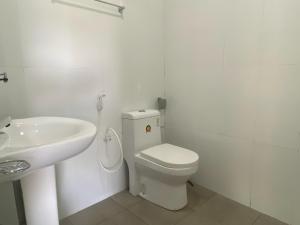 a white bathroom with a toilet and a sink at Travel Lodge City Hotel in Trincomalee