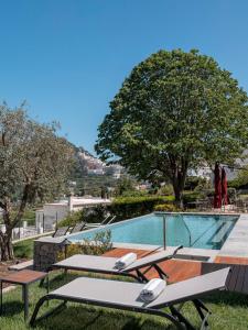 a group of picnic tables next to a swimming pool at Capri Wine Hotel in Capri