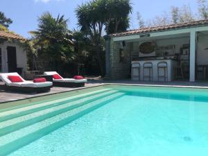 a swimming pool with two lounge chairs next to a house at Le Jardin des Portes in Les Portes