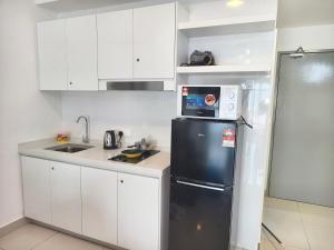 a kitchen with white cabinets and a black refrigerator at TR12 tulip elmina 5pax Big cinema movie 1 free parking in Shah Alam