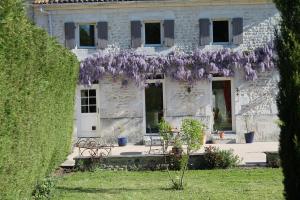 a house with a wreath of purple flowers on it at A L'Orée du Bois in Rétaud