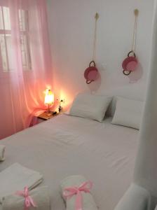 a bedroom with a white bed with a pink bow on it at Amarielia's Studios in Tinos