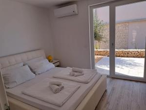 a bedroom with a white bed with towels on it at Novaedil Apartment in Povljana