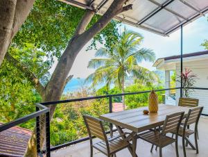 a table and chairs on a balcony with a tree at Ocean Villa in Koh Phangan