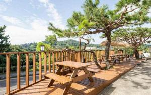 a wooden deck with picnic tables and a tree at Orange Hotel Jeju in Seogwipo