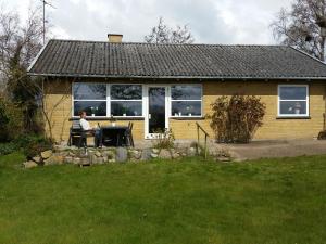 a woman sitting at a table in front of a house at BoHer Holiday Home in Røddinge