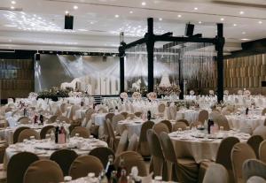 スラート・ターニーにあるBunjongburi Hotelの白いテーブルと椅子が備わる大きな宴会場