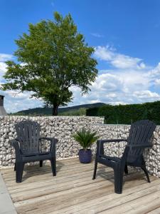 dos sillas sentadas en una terraza junto a una pared de piedra en Gîte Le vallon des vignes, en Vallon-Pont-dʼArc
