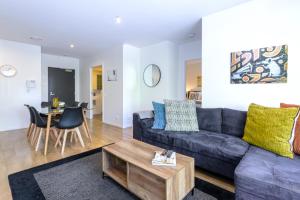a living room with a blue couch and a table at Cosmo Stays- Designer Apartment Fabulous Location in Melbourne