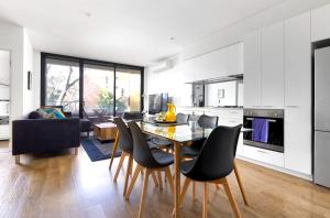 a kitchen and dining room with a table and chairs at Cosmo Stays- Designer Apartment Fabulous Location in Melbourne