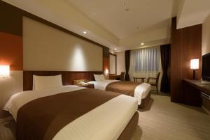 a hotel room with two beds and a television at Kokusai 21 International Hotel in Nagano