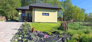 a small yellow house with flowers in a yard at Vila Veri 2 in Ostrava
