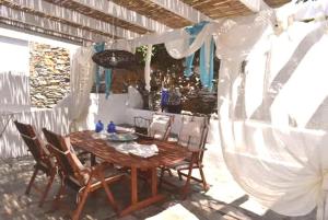 a wooden table with chairs and a white canopy at Kythnos Aegean Bliss - Kanala Seaview Getaway in Kanala