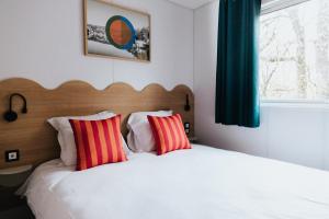 a bedroom with a bed with two red and white pillows at Camping Liberté Verdon in Artignosc-sur-Verdon