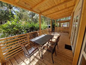 a wooden deck with a table and chairs on it at Camping Kozarica Mobile Homes in Pakoštane