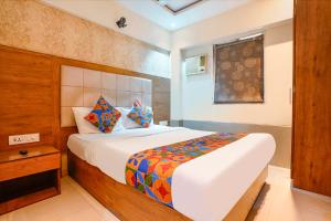 a bedroom with a large white bed with colorful pillows at FabHotel Regal Inn - In Sahar Road in Mumbai